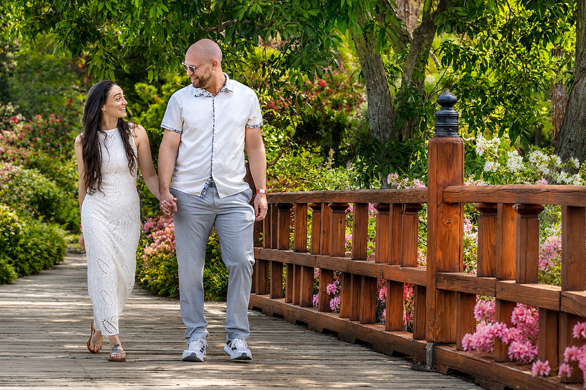 Nathan and Alyssa walk hand in hand across the wooden bridge at the Morikami Museum and Japanese Gardens before their surprise marriage proposal in Delray Beach, Florida.