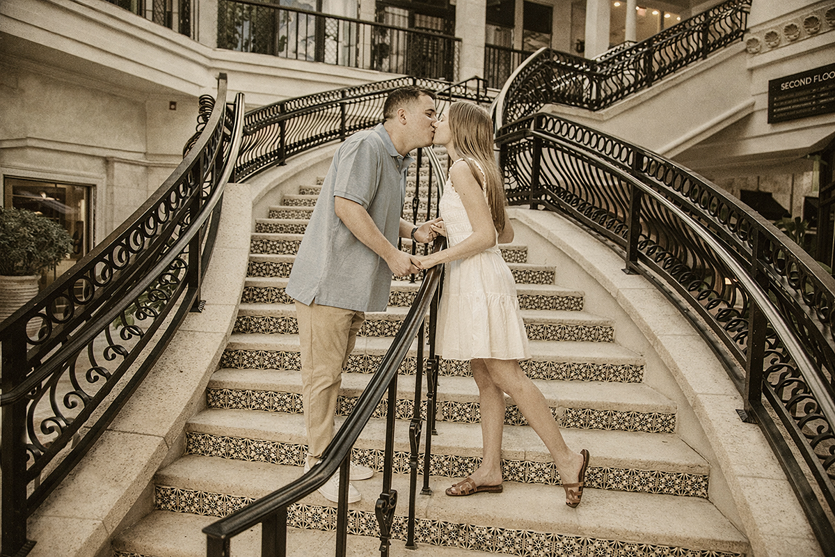 Newly engaged couple kissing on the iconic decorative staircase along Worth Avenue in Palm Beach after their surprise proposal.