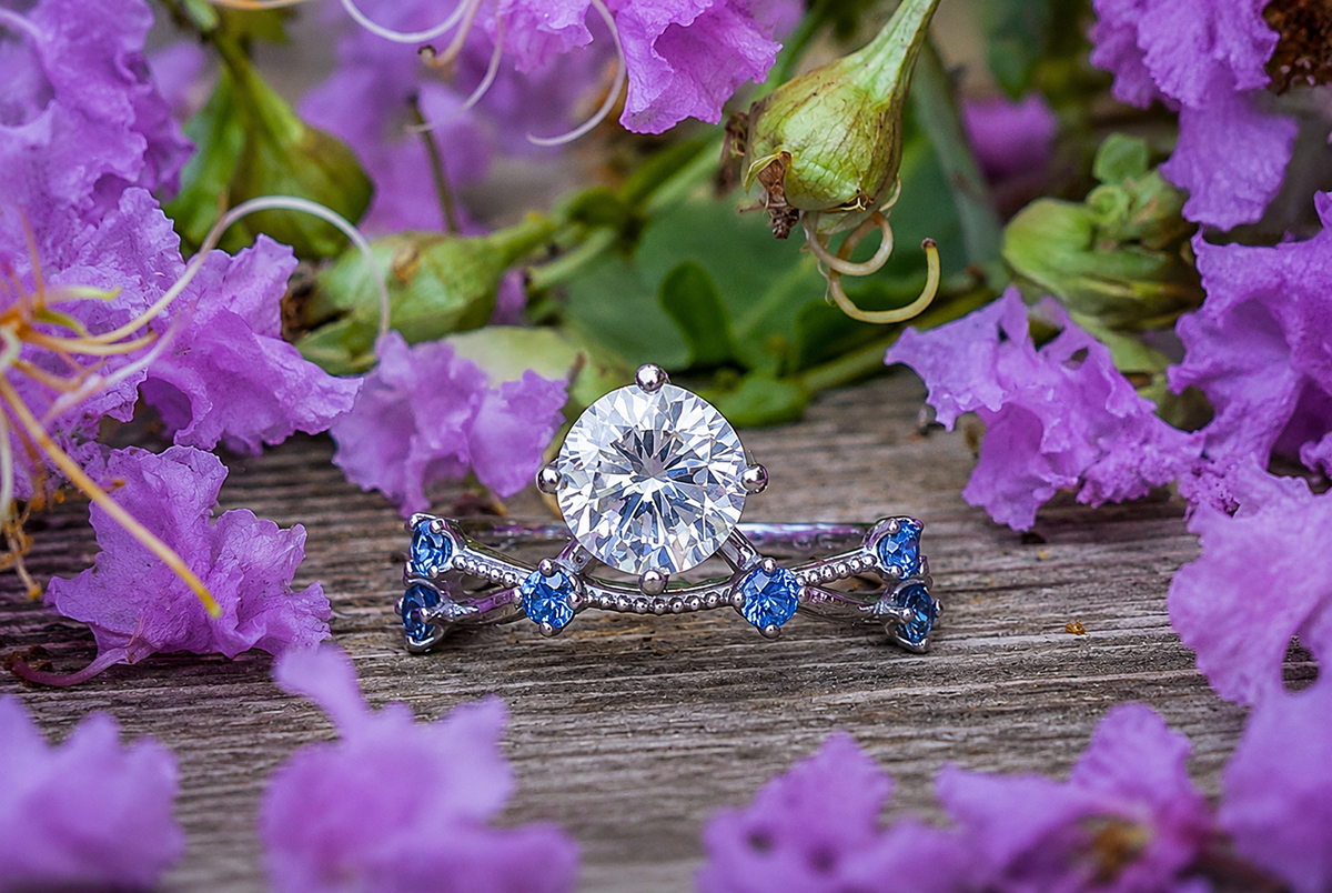 Diamond engagement ring with a sapphire wedding band surrounded by purple flowers at the Morikami Museum and Japanese Gardens in Delray Beach, Florida.Caption