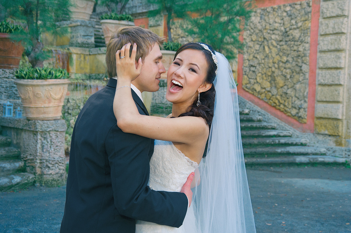 Bride and groom embrace and laugh joyfully at Vizcaya Museum and Gardens in Miami, photographed by Miami wedding photographer Jeff Kolodny.