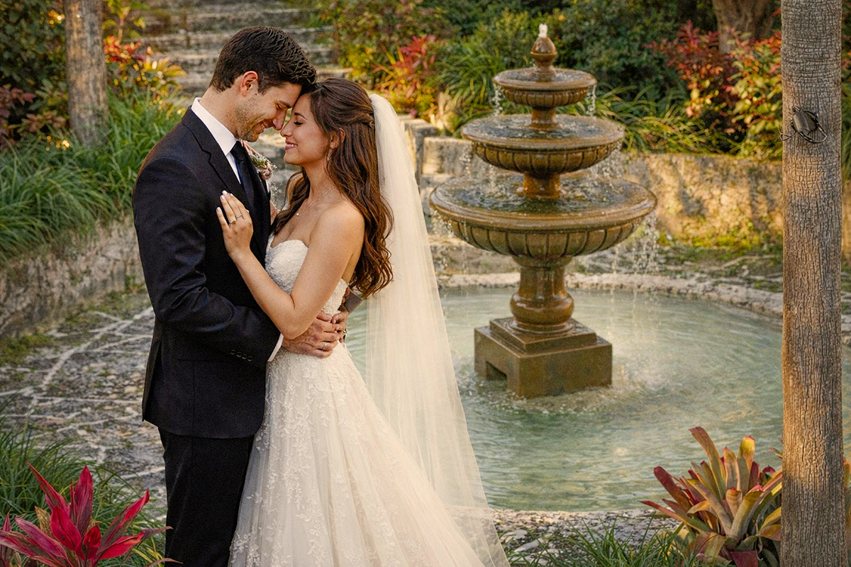 Bride and groom embracing near a fountain at Bonnet House in Fort Lauderdale, photographed from a high angle to create a dramatic and romantic perspective.