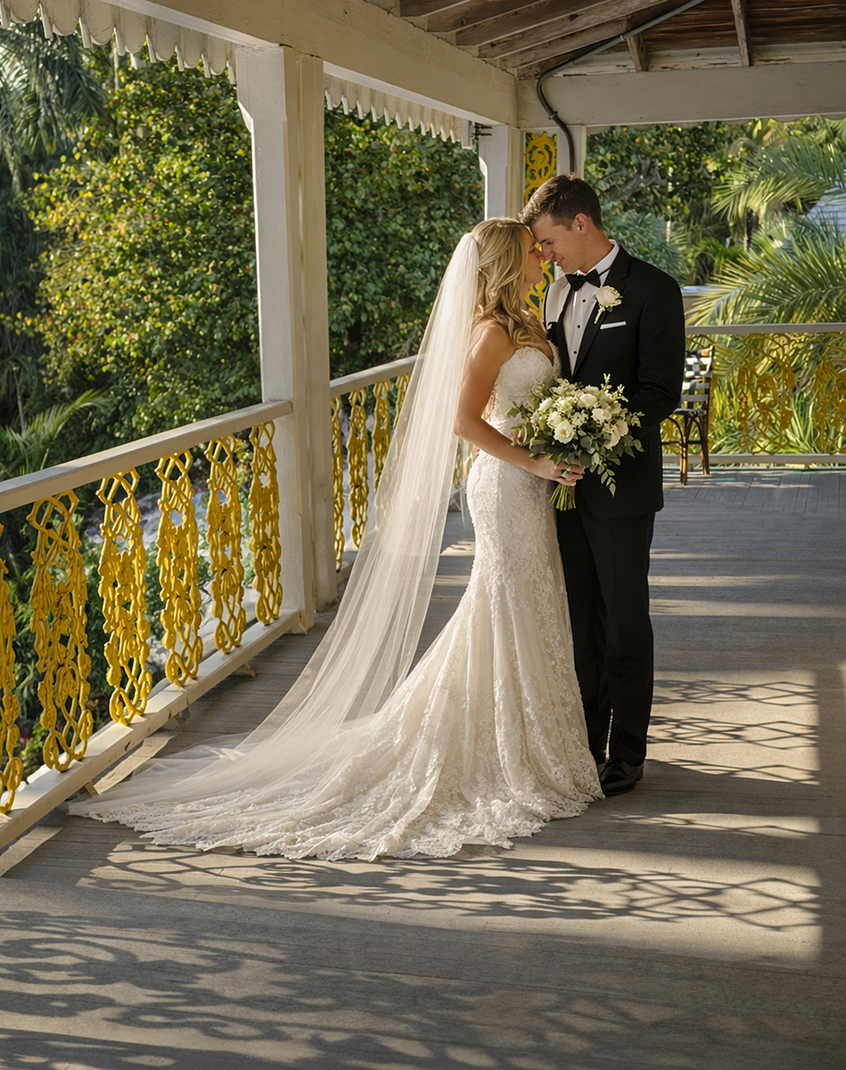 Bride and groom standing on a shaded balcony at Bonnet House in Fort Lauderdale with intricate yellow ironwork casting patterned shadows across the wooden floor.