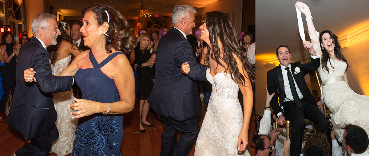 Bride and groom lifted on chairs during an energetic Jewish wedding hora, surrounded by guests dancing in a circle and celebrating.