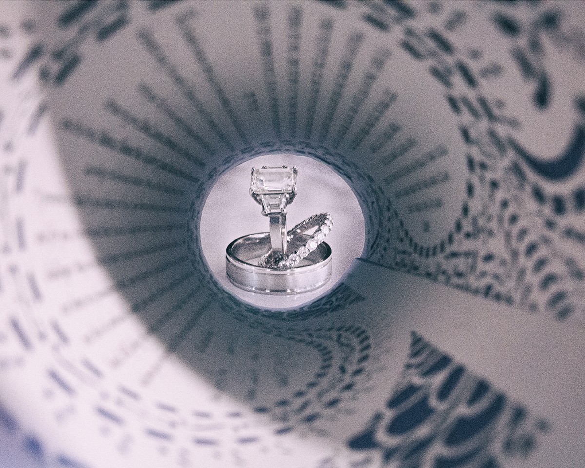 Wedding rings with diamond engagement ring inside rolled ketubah forming tunnel effect