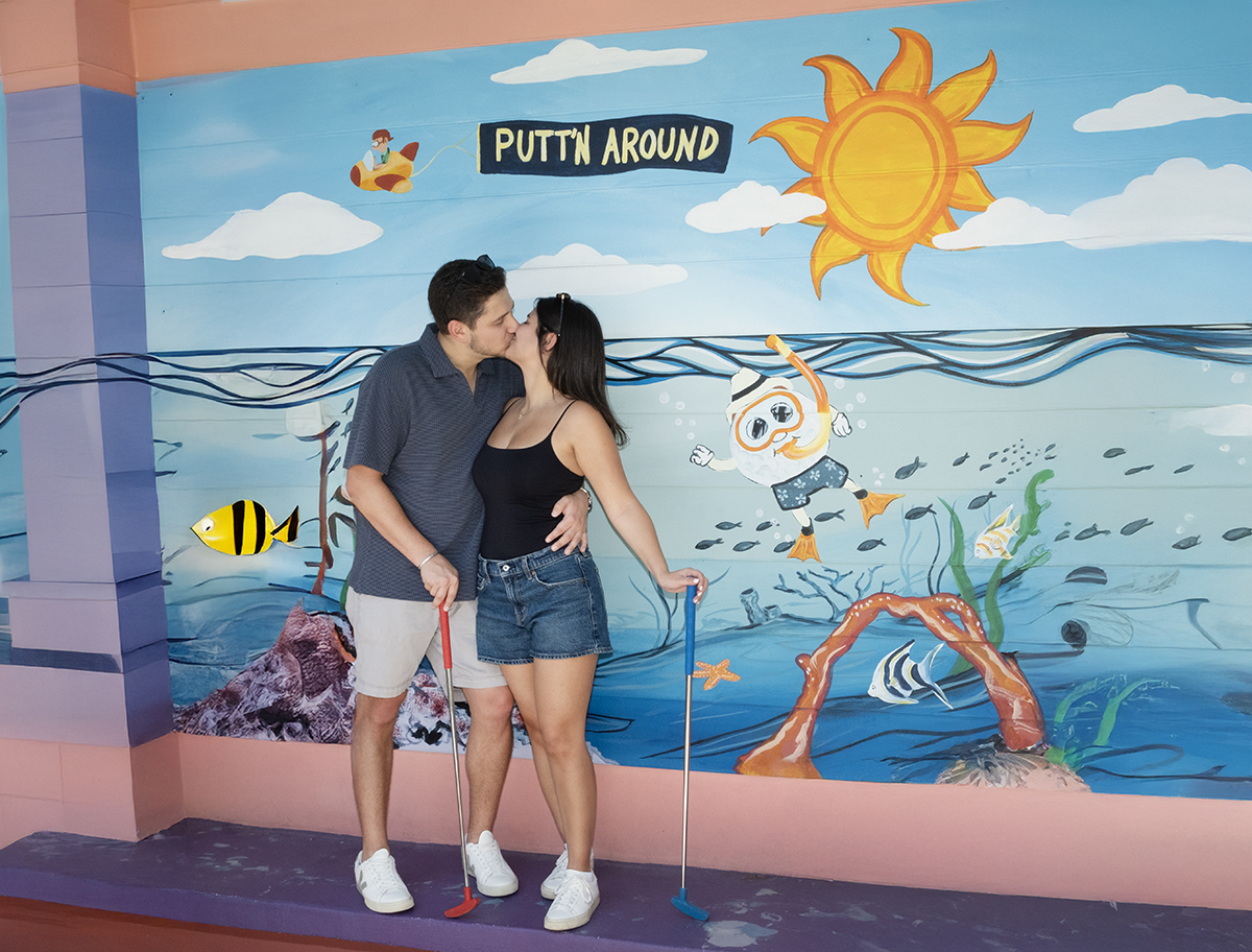 Jacob and Lauren posing together on a miniature golf course at Putt'n Around Delray Beach during their engagement photography session following a surprise marriage proposal.