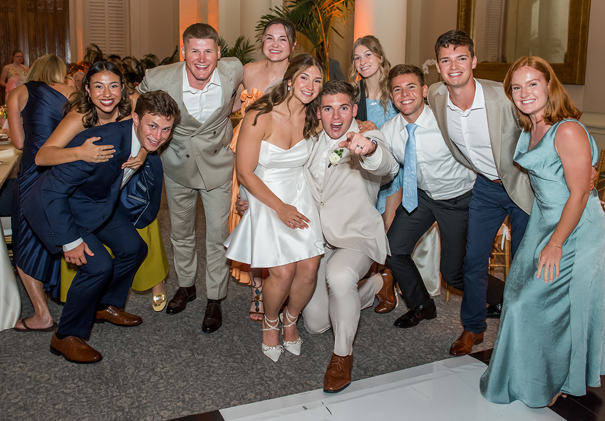 Bride and groom posing with a lively group of friends during their wedding reception at The Boca Raton in South Florida.