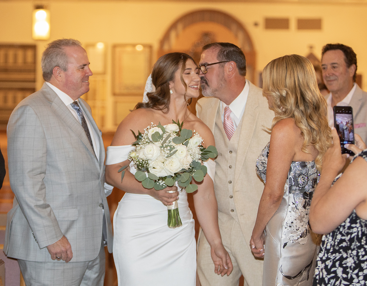 Bride Catarina begins her walk down the aisle at Our Lady of Mercy Catholic Church as family members watch with emotion during her South Florida Catholic wedding ceremony.