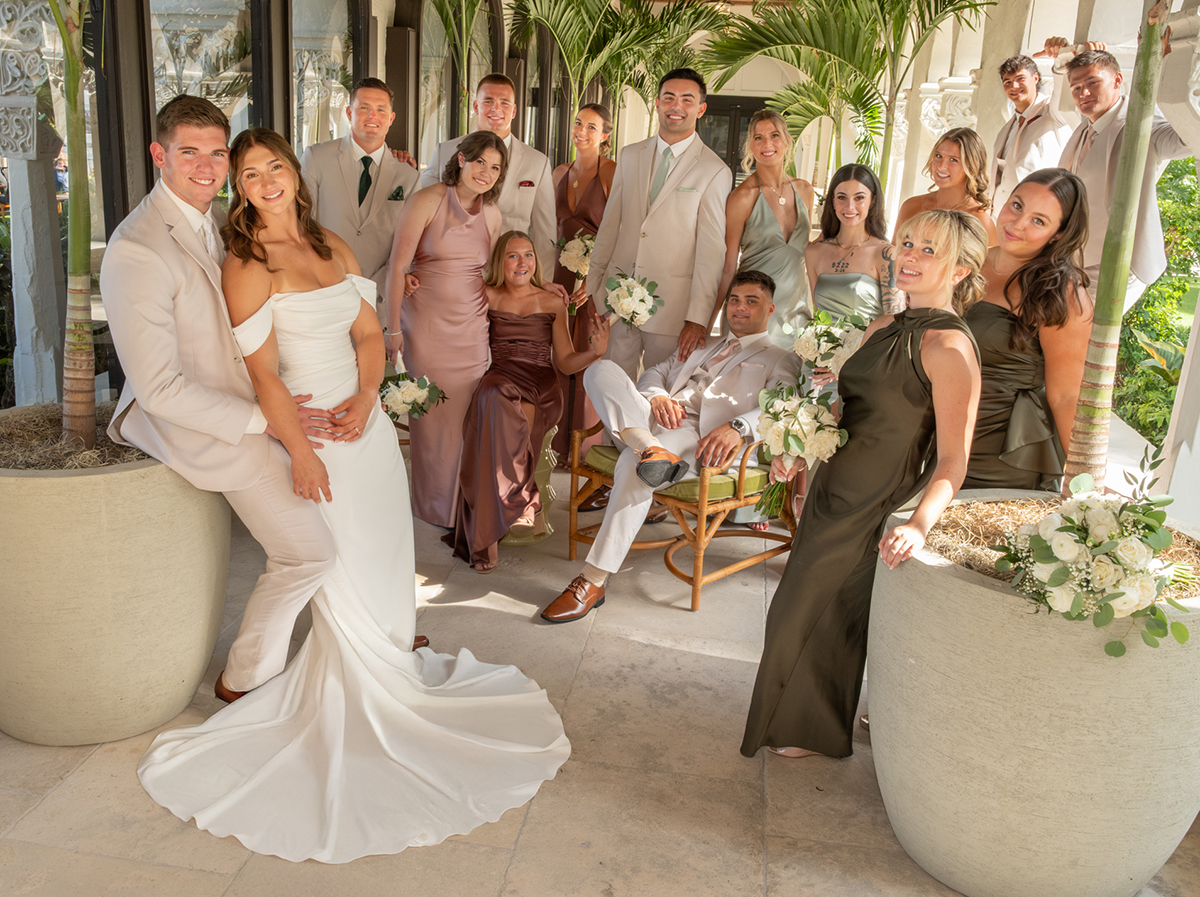 Catarina and David with their entire wedding party posed in a creative tropical setting at The Boca Raton in South Florida.
