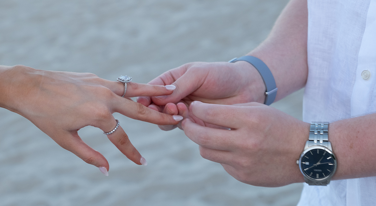 Close-up of Josh placing an engagement ring on Rachael’s finger during a Boca Raton beach proposal