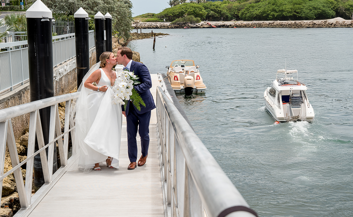 Bride and groom walking together along the waterfront dock after their first look at The Boca Raton Beach Club.