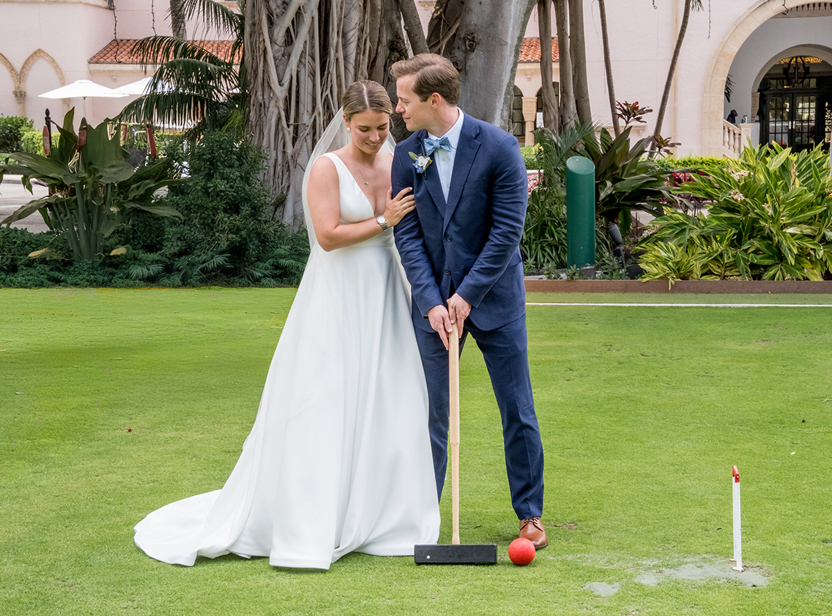 Bride and groom sharing a playful moment on the croquet lawn during their wedding at The Boca Raton.
