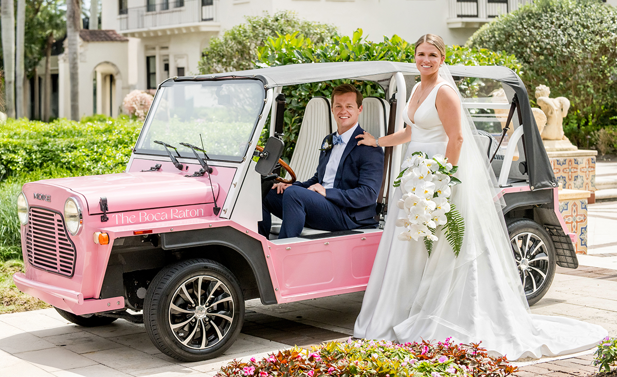 Bride and groom posing with The Boca Raton’s pink Moke during their wedding portraits at the resort.