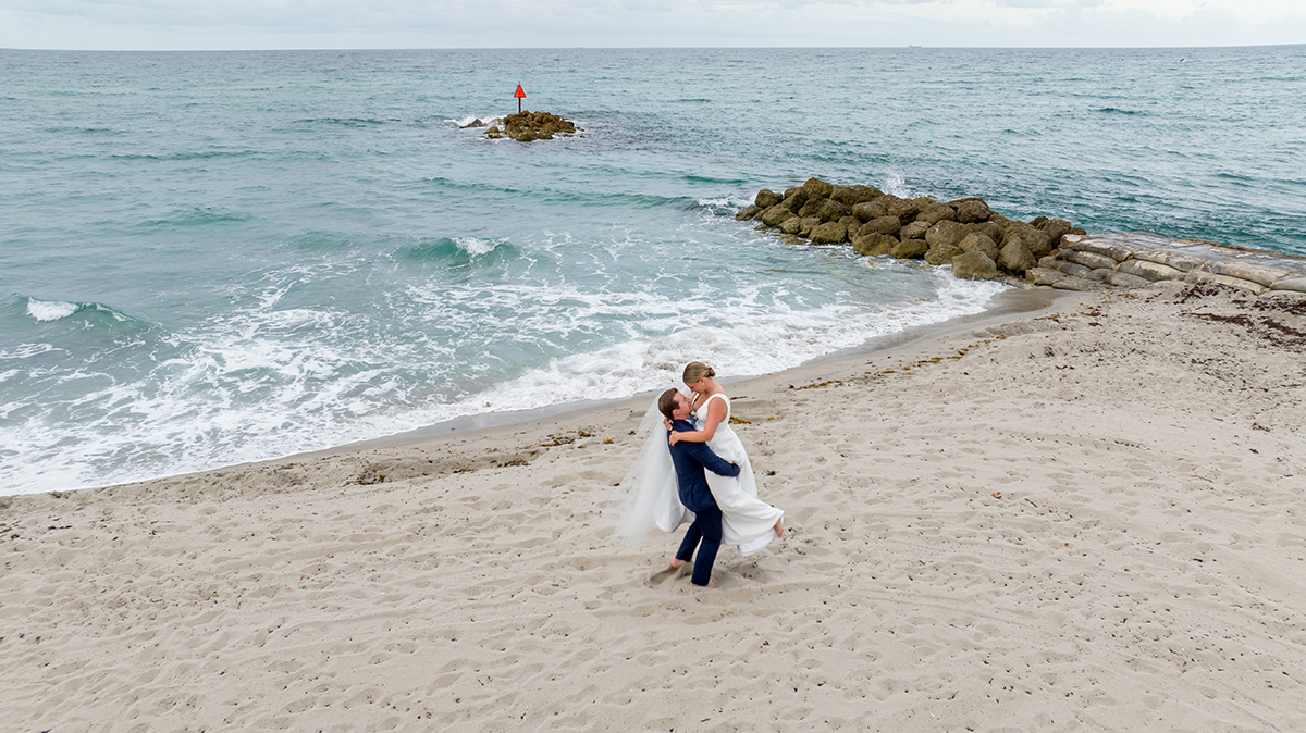 Aerial wedding portrait of bride and groom on the beach beside the Atlantic Ocean at The Boca Raton Beach Club.