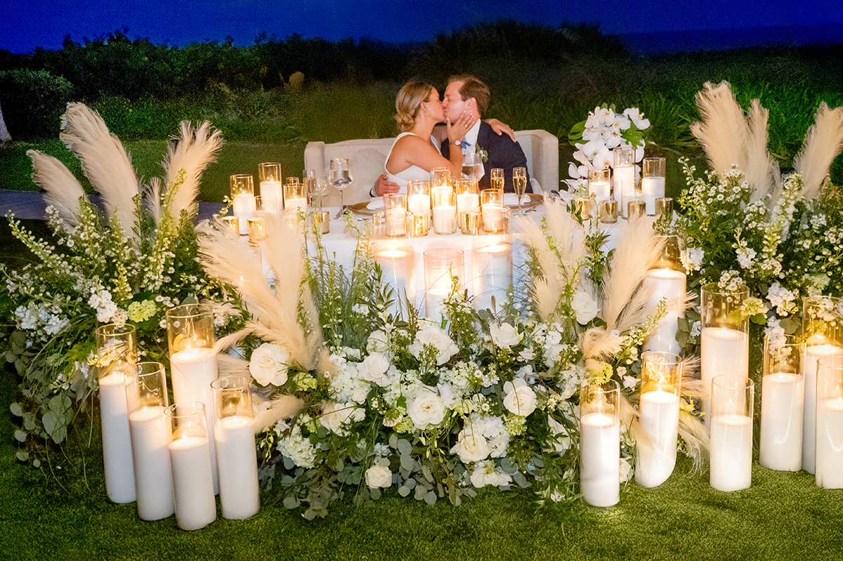 Bride and groom kissing at their candlelit head table during their wedding reception at The Boca Raton Beach Club