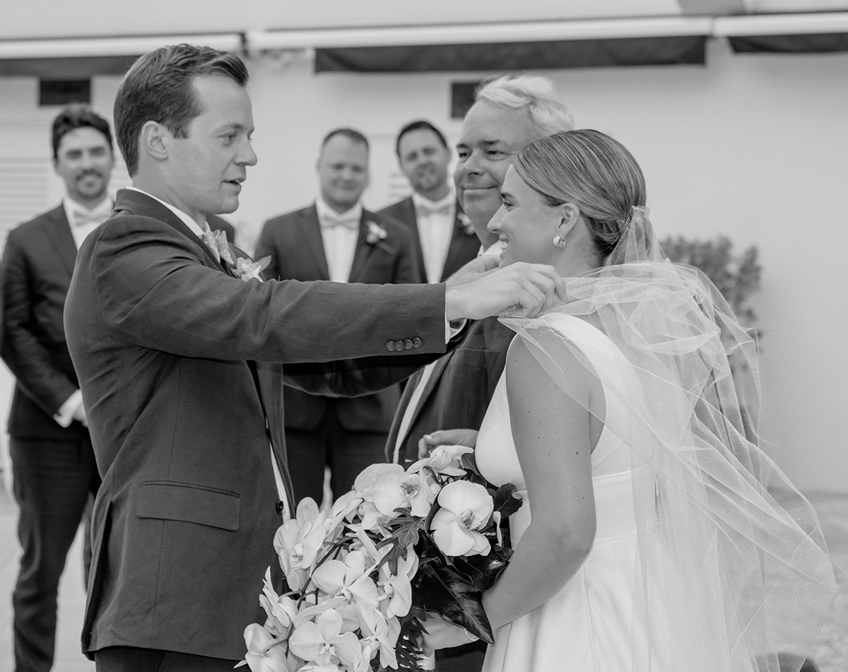 Jack gently adjusts Katie’s veil as her father smiles during their wedding ceremony at The Boca Raton Beach Club.
