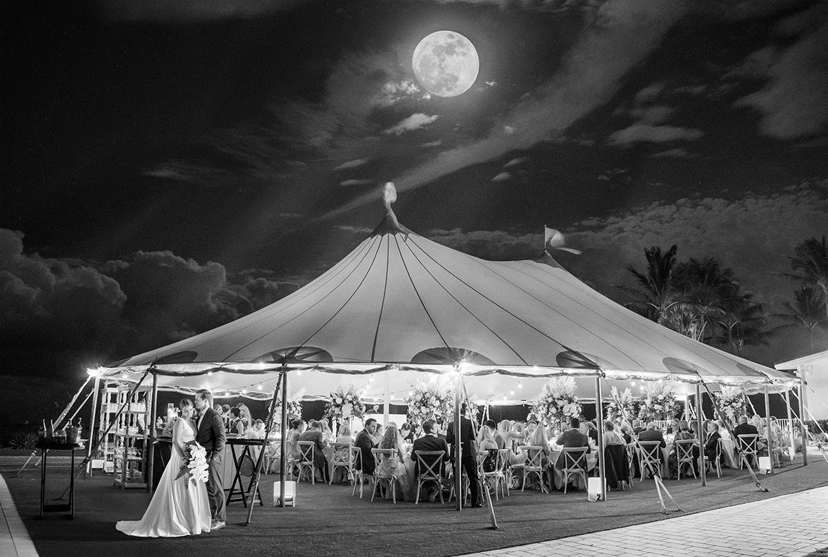 Black-and-white nighttime view of Katie and Jack beside their wedding reception tent at The Boca Raton Beach Club beneath a dramatic full moon.